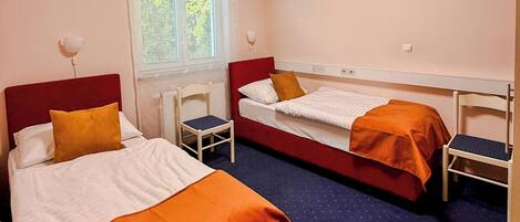A room with two beds, a window, a desk, and a chair.