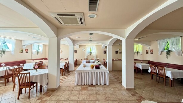 A spacious dining area with high ceilings, arched columns, and multiple tables and chairs. - Hotel Imperium (Moravske Toplice)