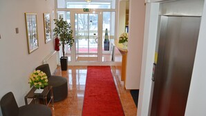 A hotel lobby with a red carpet, seating area, and a reception desk. - Hotel Imperium (Moravske Toplice)