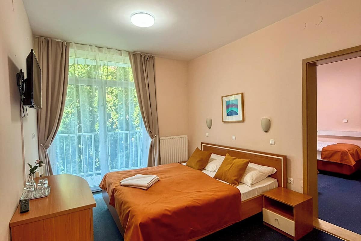 Ein Hotelzimmer mit Bett, Nachttisch und Blick auf Grünfläche.