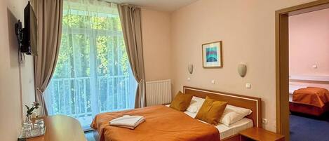 Habitación de hotel con cama, mesita de noche y vista a zonas verdes.