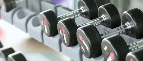 A rack of black dumbbells with weight markings, arranged in rows.