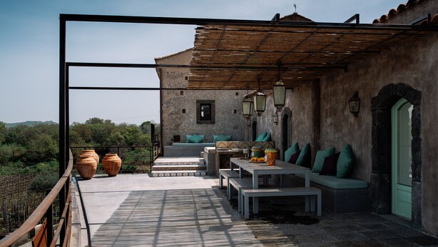 Un patio al aire libre con una zona de estar, una mesa y dos jarrones grandes.