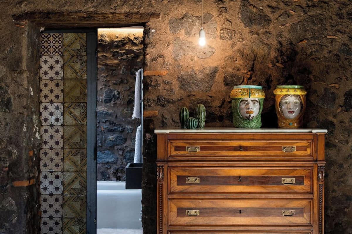 A rustic stone wall with a wooden dresser and decorative items.