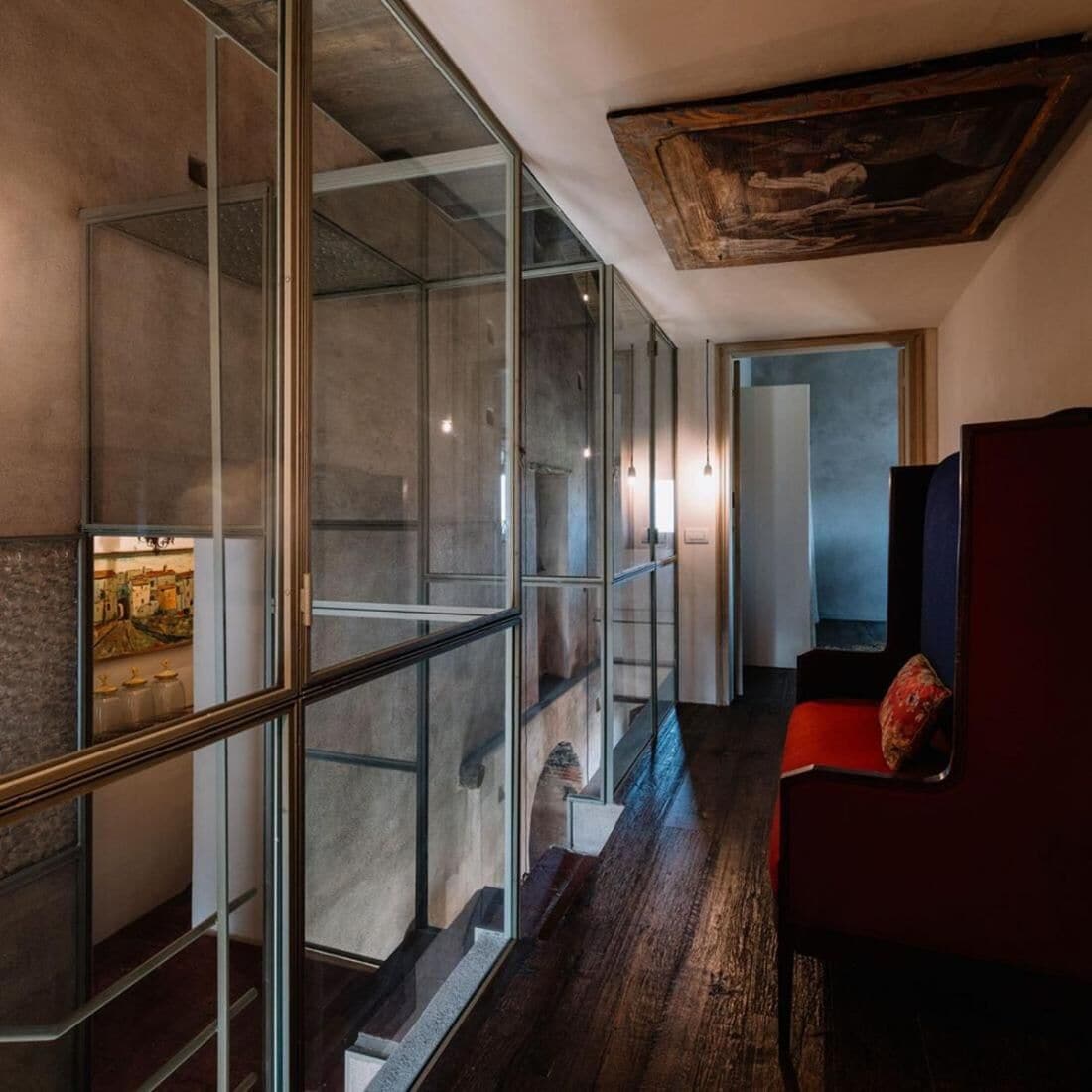 Un interior moderno con un separador de vidrio, una escalera y una silla roja.