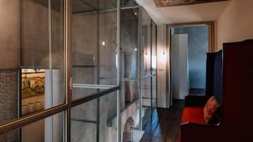 A modern interior with a glass partition, a staircase, and a red chair.