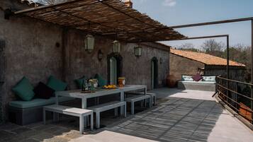 An outdoor patio with a table and benches, a cushioned seating area, and a pergola.
