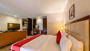 Hotelkamer met een groot bed, een bureau met een televisie, een spiegel en een deur naar een badkamer.