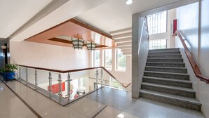 Een ruime binnenruimte met een gepolijste vloer, een trap met houten leuning en een glazen balustrade met uitzicht op een lager gelegen niveau.