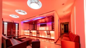 Een moderne woonkamer met een bar, lederen zitplaatsen en hanglampen.