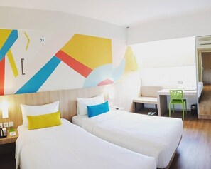 Hotellihuone, jossa on kaksi sänkyä, työpöytä ja tuoli.