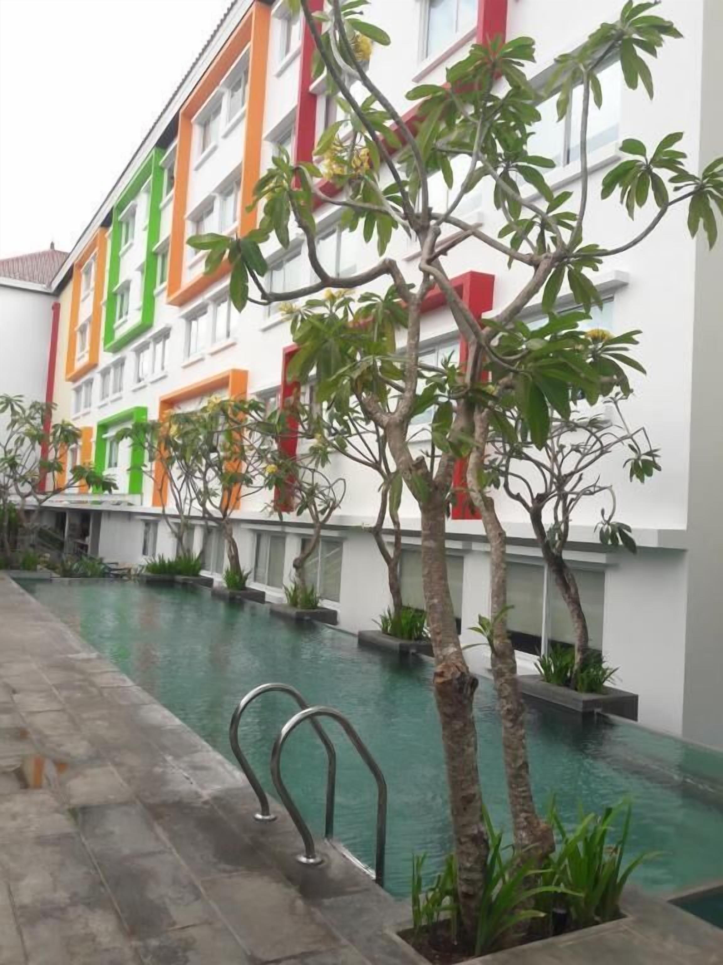 A modern building with colorful facades and a pool area with metal railings.
