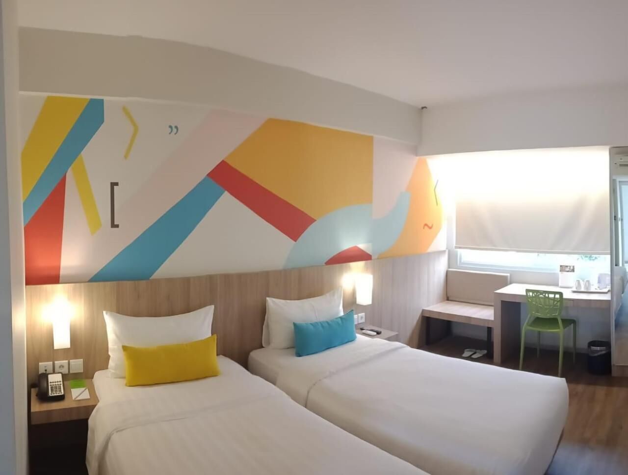 A hotel room with two beds, a desk, and a chair.