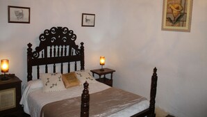 Une chambre à coucher avec un lit en bois, deux tables de chevet avec des lampes et des tableaux encadrés accrochés aux murs.