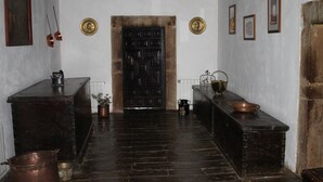 Un couloir doté d’un parquet en bois foncé, d’une porte noire et d’un mur blanc orné de tableaux encadrés et d’une plaque en laiton.