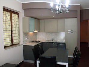 A compact kitchen with a dining area, featuring a gas stove, sink, and modern cabinetry. - Villa Palma (Avella)