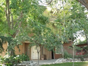 A building with a brick facade, a white door, and a small garden with rocks and trees. - Villa Palma (Avella)