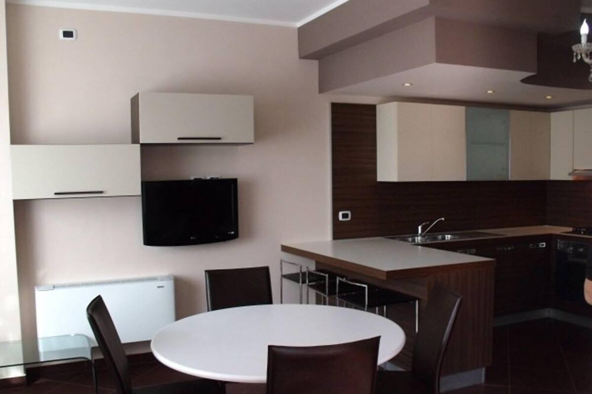 A modern kitchen with a central island, built-in appliances, and a flat-screen TV.