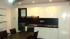A modern kitchen with white cabinets, a black countertop, and a dining area with a table and chairs. - Villa Palma (Avella)