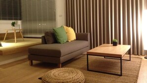 A modern living room with a sofa, a coffee table, and a small plant. - Missy House (Wujie)