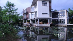 A modern house with a large pond in front, surrounded by greenery. - Missy House (Wujie)