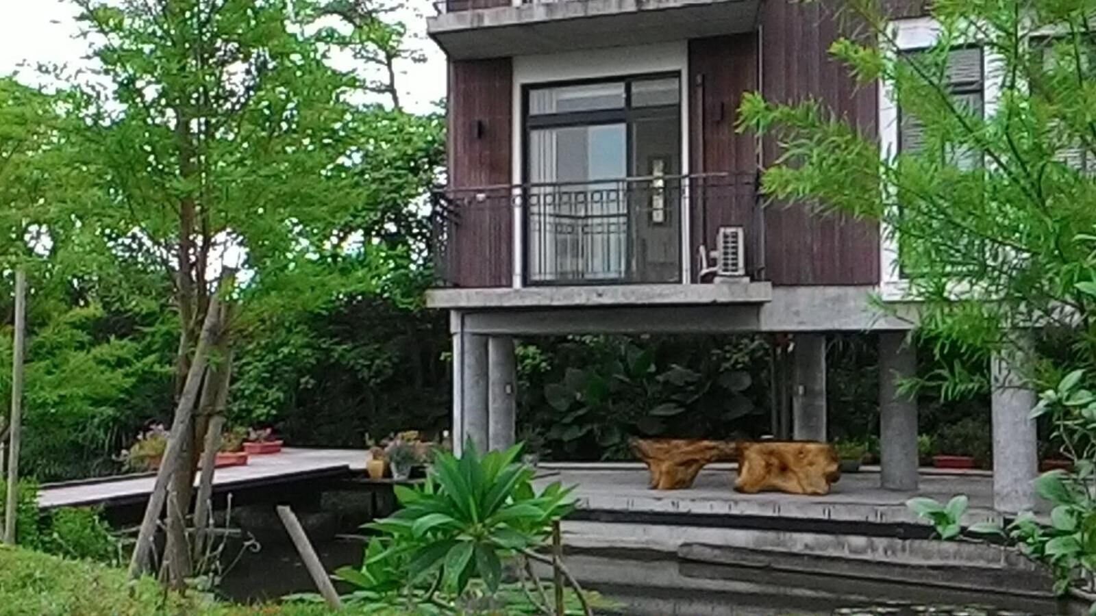 A two-story building with a balcony, surrounded by greenery.