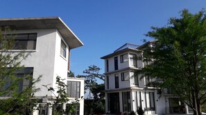 A modern multi-story building with large windows and balconies, surrounded by greenery. - Missy House (Wujie)
