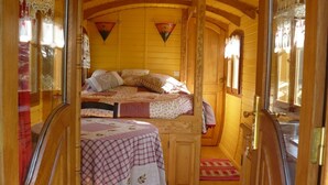 Un dormitorio acogedor y compacto con cama, una mesita pequeña y una ventana.