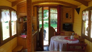 Una cabaña acogedora con interior de madera, un comedor con mesa y sillas, y una cocina con microondas.