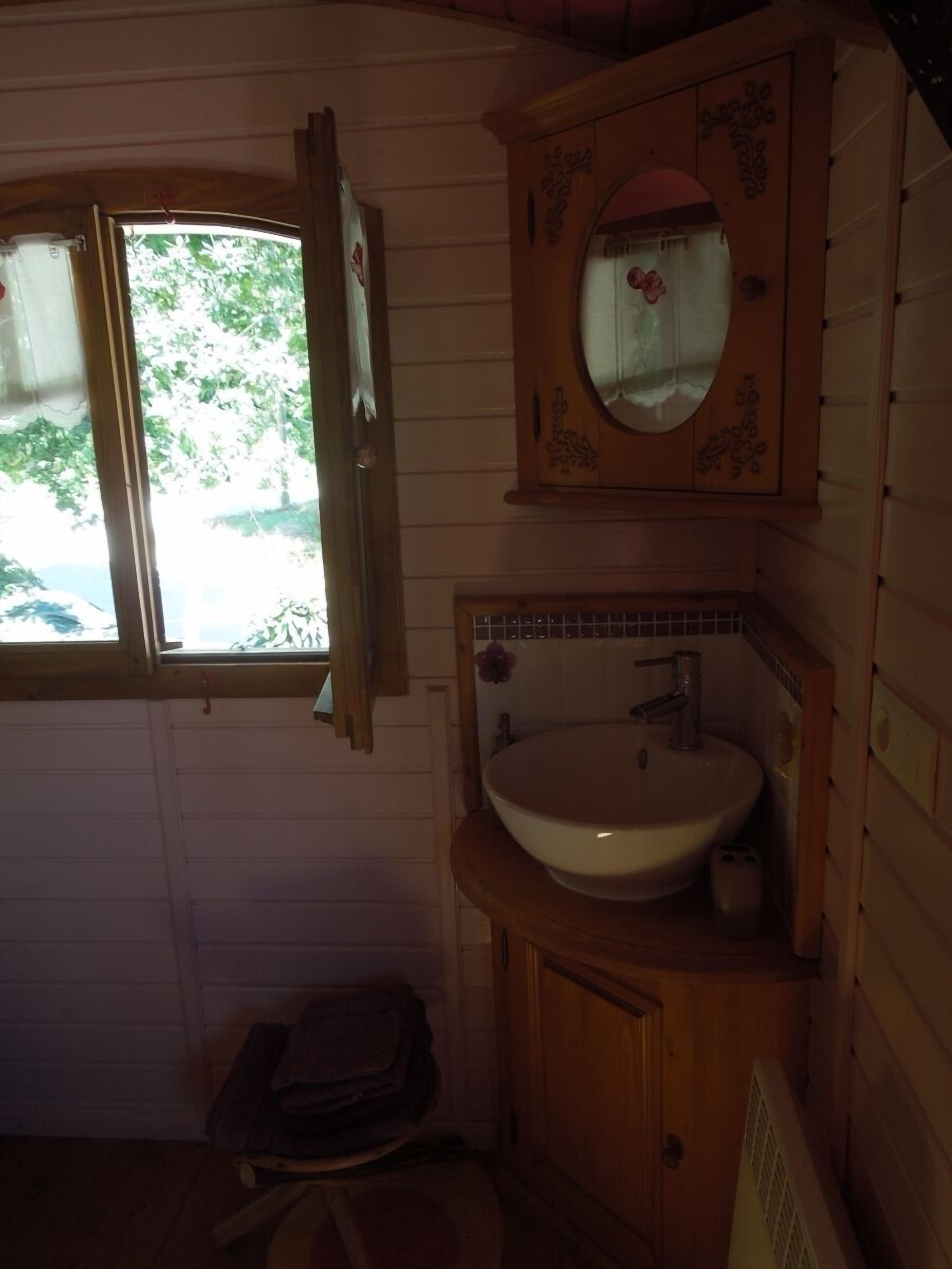 A small bathroom with a wooden vanity, a sink, and a mirror.