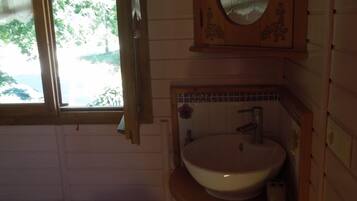 A small bathroom with a wooden vanity, a sink, and a mirror.
