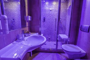 Un baño moderno con ducha de vidrio, un lavabo blanco y un inodoro.
