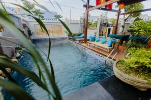 A swimming pool with lounge chairs and a wooden deck. - Home River Villa (Da Nang)