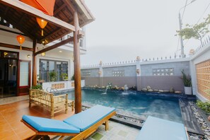 A pool area with lounge chairs, a wooden pergola, and a water feature. - Home River Villa (Da Nang)