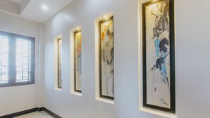 A hallway with framed abstract art on the walls, a window on the left, and a tiled floor. - Home River Villa (Da Nang)