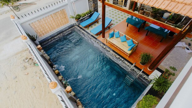 A rooftop pool area with a pool, lounge chairs, and a seating area with tables and chairs. - Home River Villa (Da Nang)