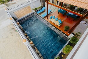 Zona de piscina en la azotea, con piscina, sillas de descanso y un área de estar con mesas y sillas.