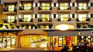 A multi-story hotel with balconies, a central entrance, and a parking area. - Il Palazzo Boutique Apartment Hotel (Cairns)