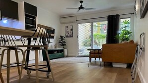 A modern living room with a dining area, a sofa, a coffee table, and a view through a glass door. - Il Palazzo Boutique Apartment Hotel (Cairns)