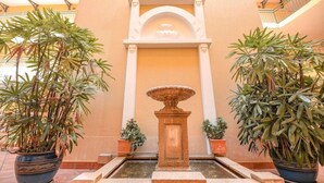 A courtyard with a central fountain, surrounded by potted plants and a decorative archway. - Il Palazzo Boutique Apartment Hotel (Cairns)