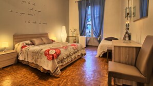 Ein Schlafzimmer mit Holzboden, einem Bett mit roter und weißer Decke, einem Schreibtisch mit Lampe und einem Stuhl.