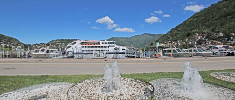 A ferry terminal with a large white ferry docked, surrounded by a mountainous landscape and a clear blue sky.