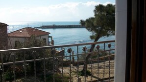 Un balcon avec vue sur la mer, une jetée et un bâtiment avec un toit rouge.