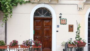 Un bâtiment doté d’une grande porte en bois, de plantes en pot et de mobilier d’extérieur.