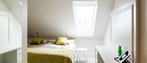 Un dormitorio con cama, escritorio, silla, una mesita y una ventana.