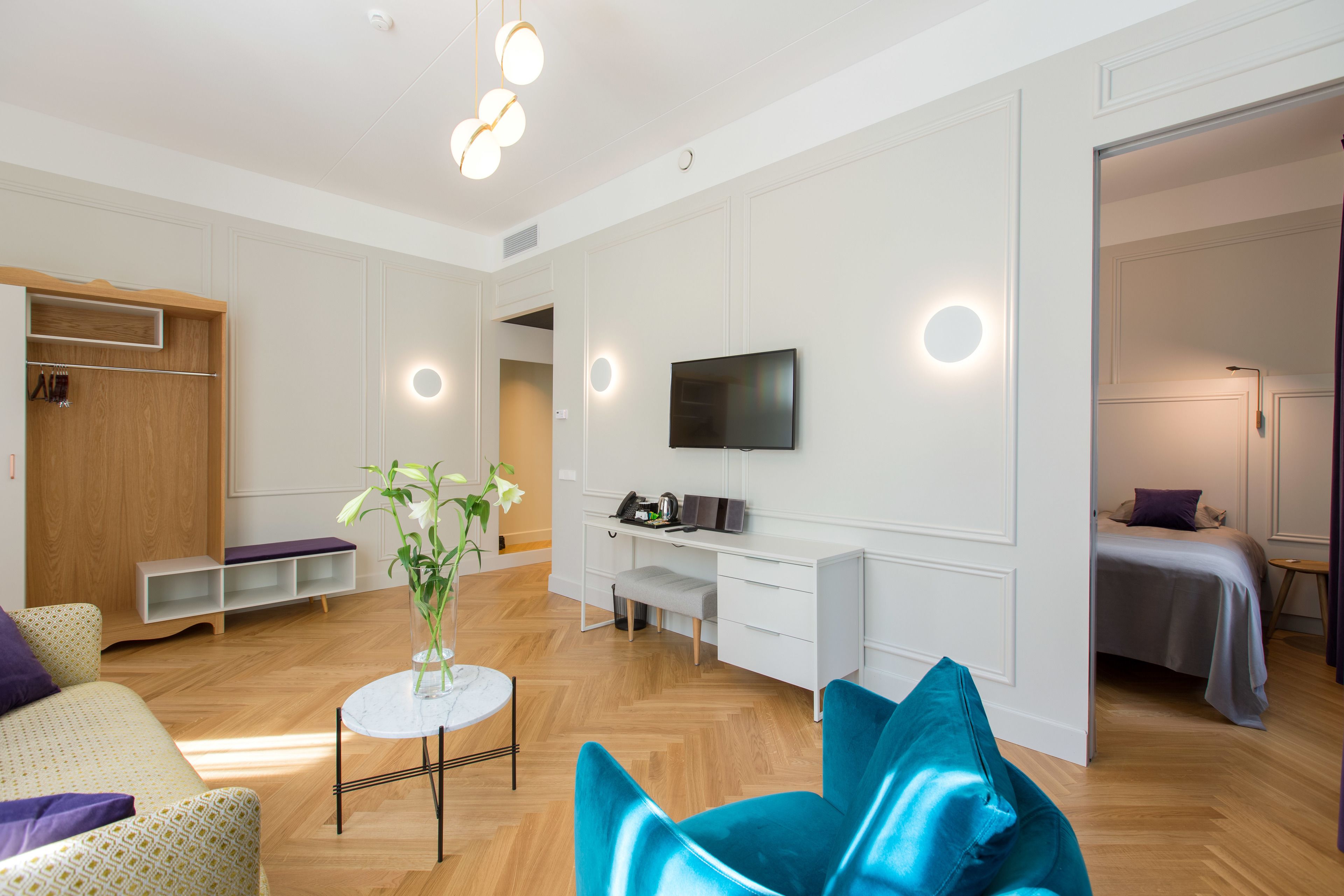 A modern living room with a sofa, a coffee table, a blue chair, a TV, and a desk.