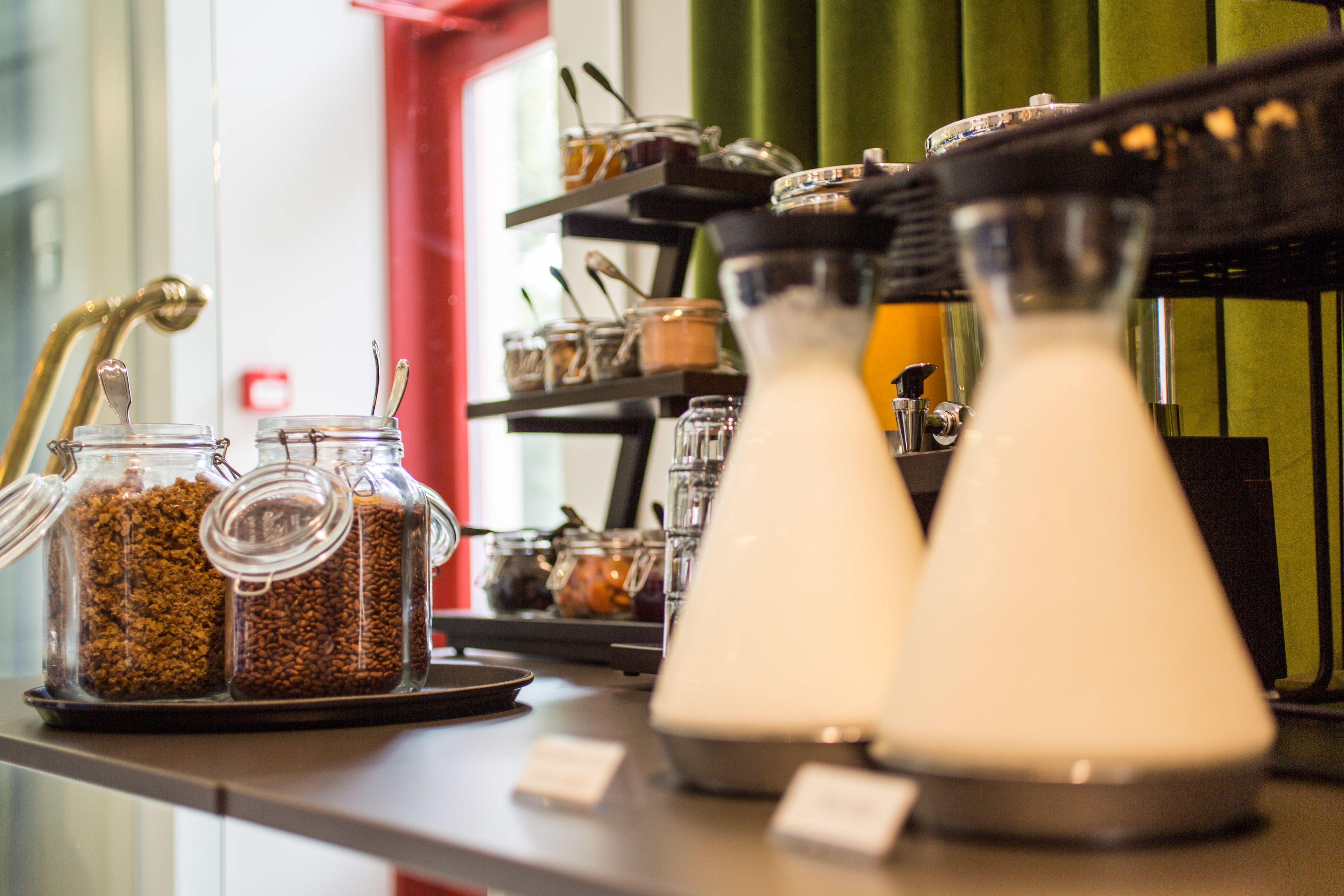 A coffee station with jars of coffee beans and milk dispensers.
