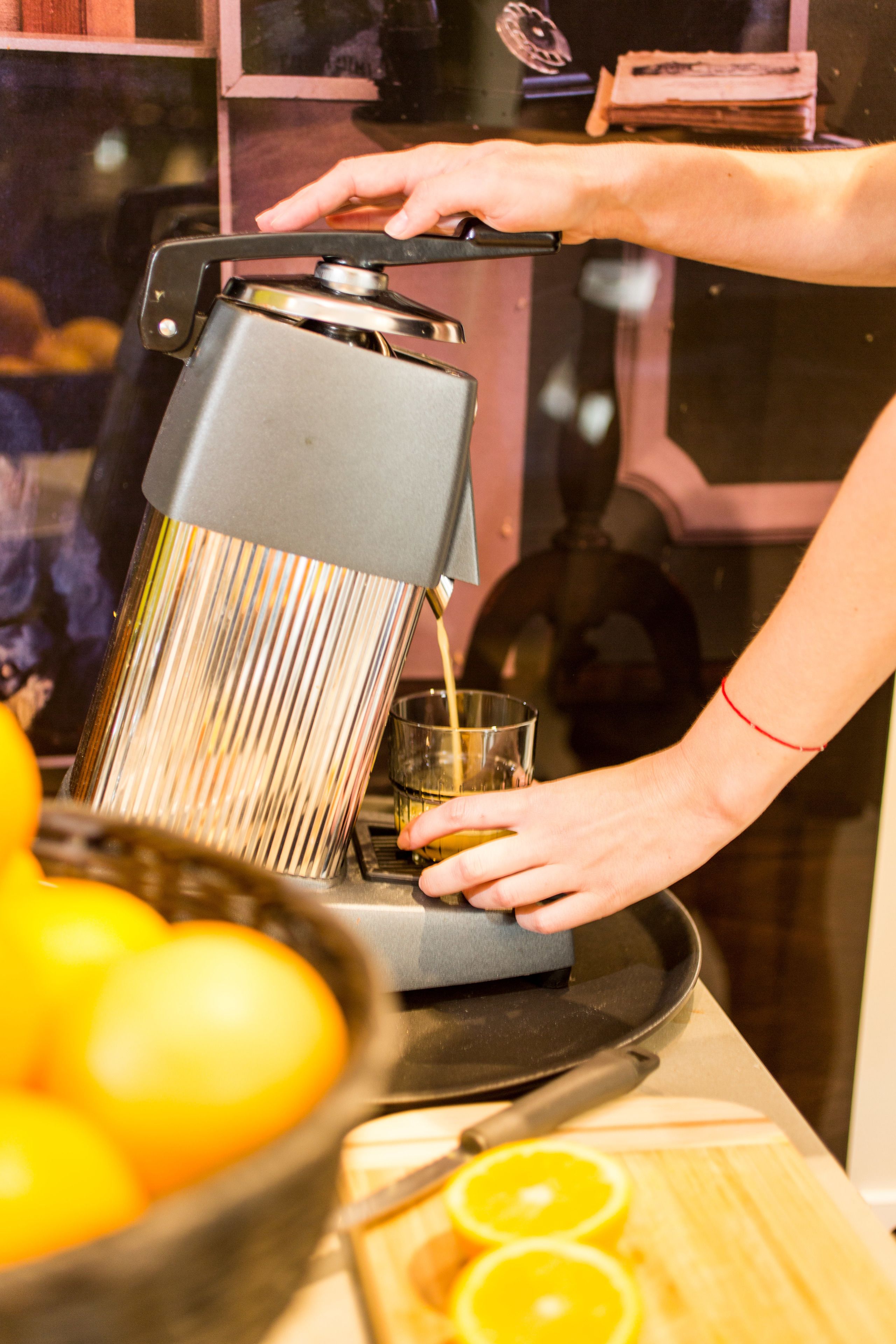 A person using a manual juicer to extract juice from oranges.