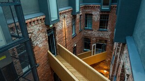 Un intérieur à plusieurs niveaux, avec des murs en briques apparentes, des plateformes en bois et une verrière.