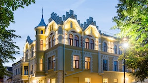 Un bâtiment historique doté d’une tourelle et de nombreuses fenêtres, qui pourrait être un hôtel ou un bâtiment public.